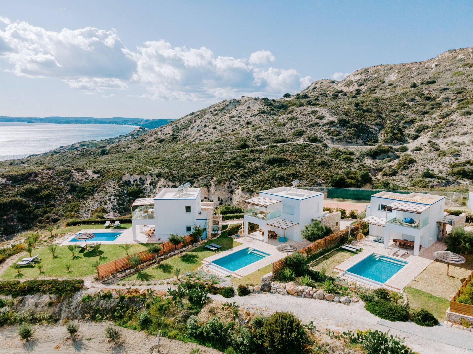 The three villas with private pools on the hillside of Antimachia, sea behind