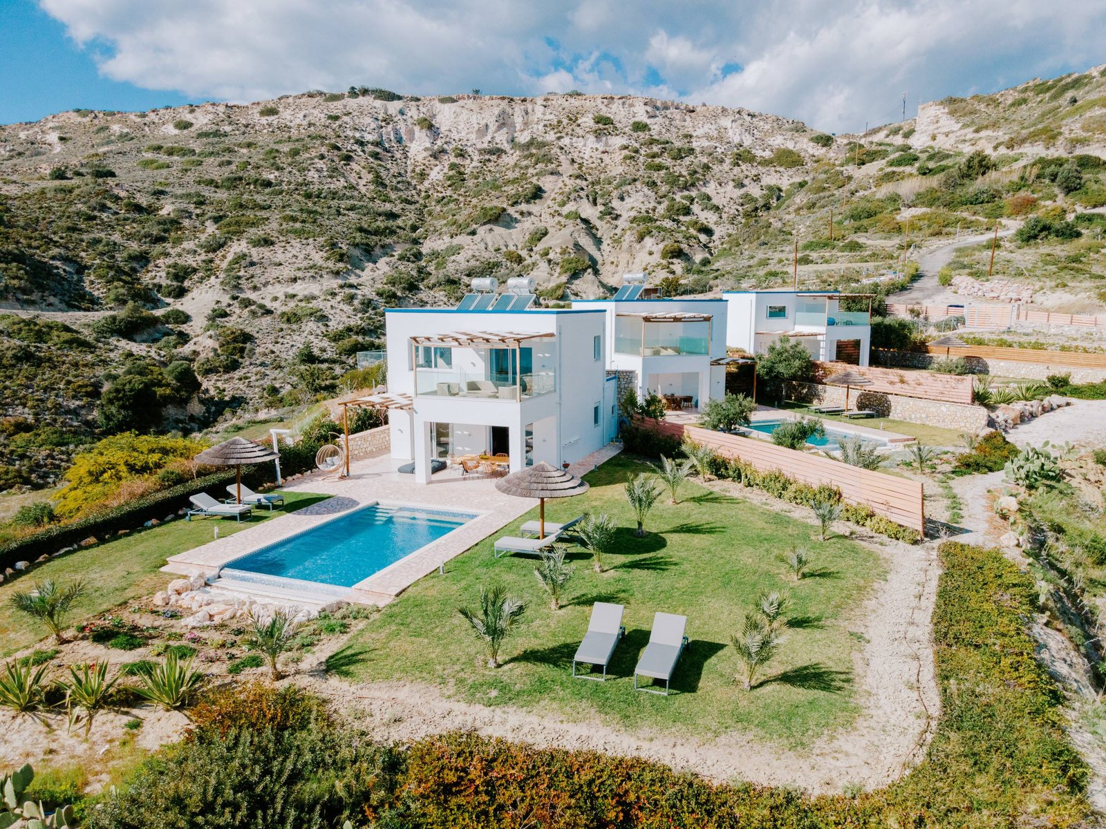 White villa with private pool and lawn surrounded by Kos hills