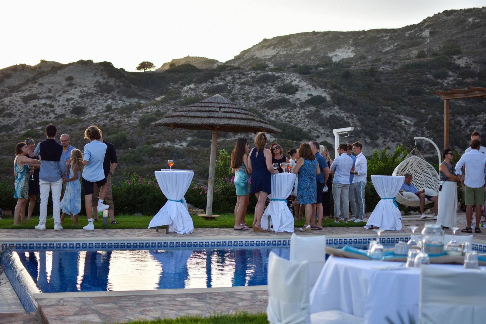 Cocktail reception by the pool with sea and hills behind