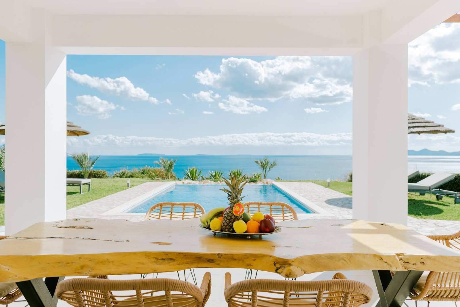 Wooden dining table with fruit on the terrace, pool and sea view