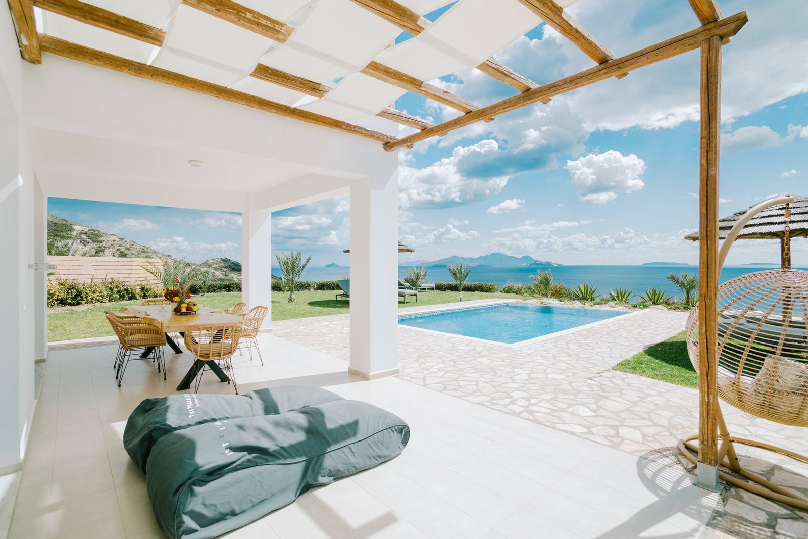 Shaded pergola terrace with lounge cushions next to the pool